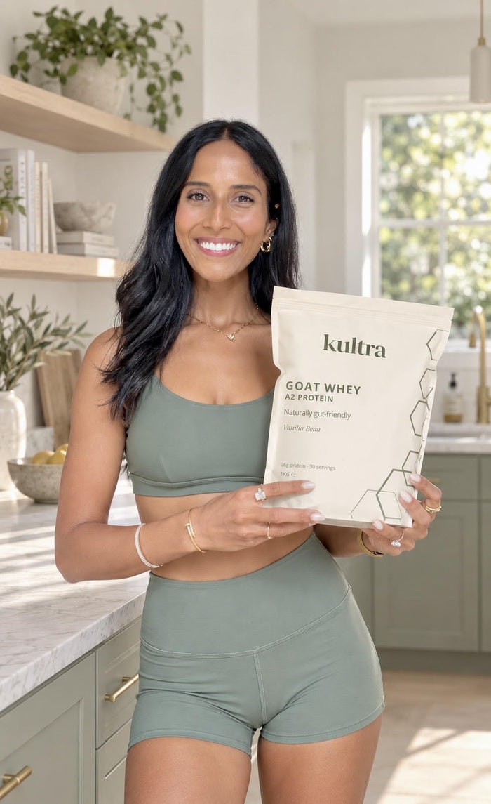 Woman in a sunny kitchen holding a bag of Kultra Goat Whey Protein