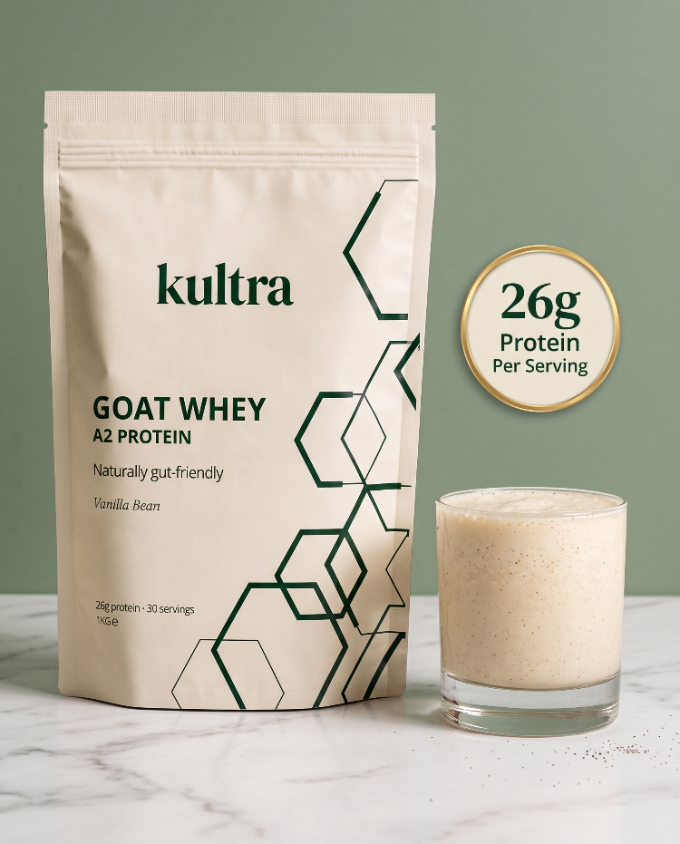 A stand-up pouch of kultra Goat Whey A2 Protein next to a glass of the prepared vanilla bean protein shake, set against a sage green background and white marble surface.